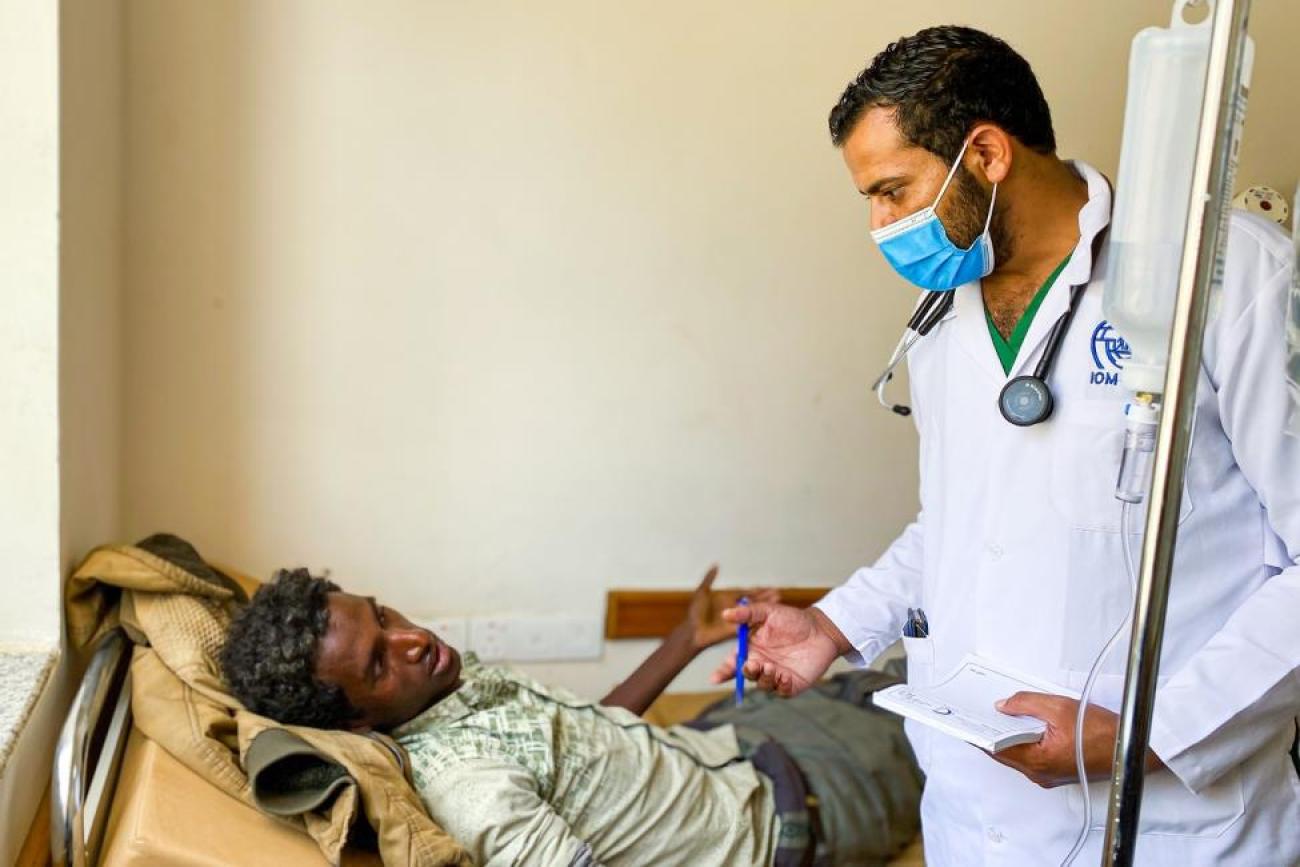 طبيب في مستشفى مُنَبِّه يفحص حالة مهاجر مريض في غرفة الطوارئ.